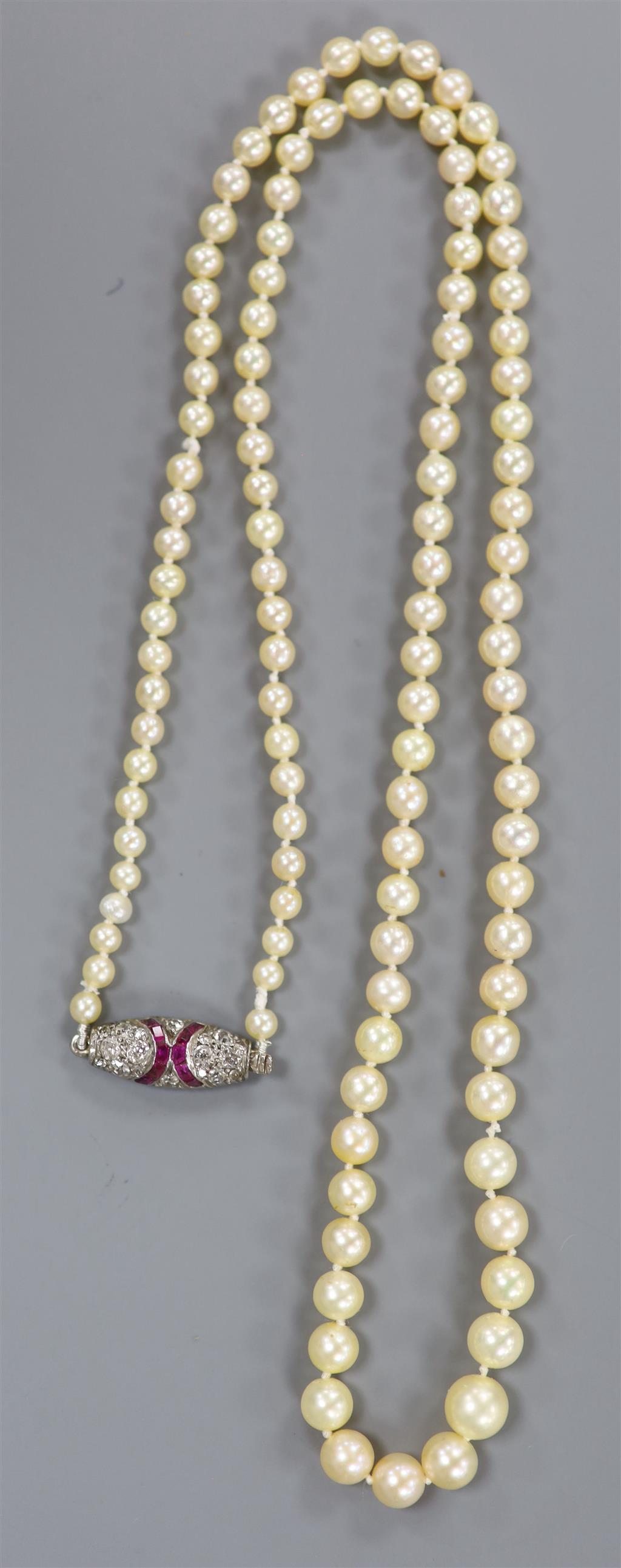 An early 20th century single strand graduated seed pearl necklace, with white metal ruby and diamond set clasp,